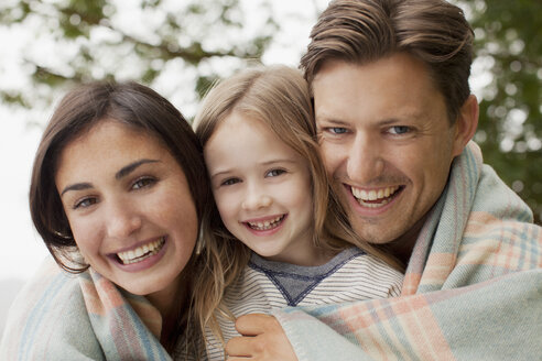 Nahaufnahme einer lächelnden, in eine Decke eingewickelten Familie - CAIF00095