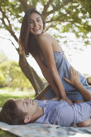 Porträt eines lächelnden Paares auf einer Decke im Gras, lizenzfreies Stockfoto