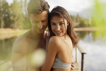 Porträt eines lächelnden Paares, das sich am Seeufer umarmt - CAIF00134