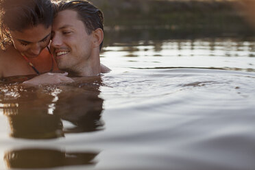 Lächelndes Paar beim Schwimmen im See - CAIF00136