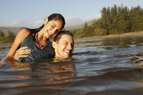 Porträt eines lächelnden Paares beim Schwimmen im See, lizenzfreies Stockfoto