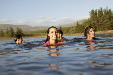 Lächelnde Freunde beim Schwimmen im See - CAIF00141