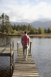 Man walking along dock over lake - CAIF00142