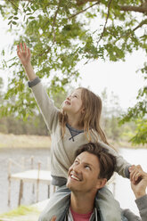 Daughter on father’s shoulders reaching for branch - CAIF00168