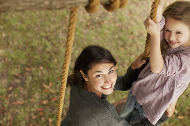 Portrait of smiling mother and daughter on swing - CAIF00176