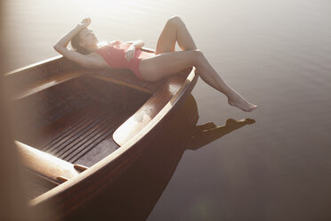 Gelassene Frau beim Sonnenbaden im Boot auf dem See - CAIF00187