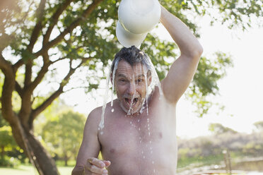 Porträt eines begeisterten Mannes, der Wasser über den Kopf gießt - CAIF00190
