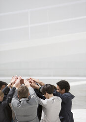 Business people with arms raised in huddle - CAIF00212