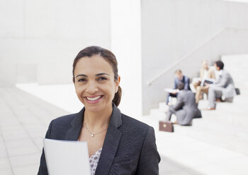 Porträt einer selbstbewussten Geschäftsfrau mit Mitarbeitern im Hintergrund - CAIF00213