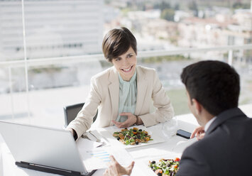 Businessman and businesswoman with laptop meeting over lunch - CAIF00223