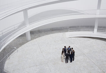 Business people standing in circle of modern courtyard - CAIF00237