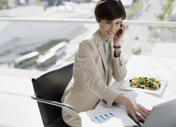 Geschäftsfrau beim Multitasking am Schreibtisch - CAIF00249