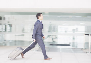 Geschäftsmann mit Koffer eilt den Flughafenkorridor entlang - CAIF00251