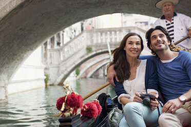 Smiling couple riding in gondola in Venice - CAIF00316