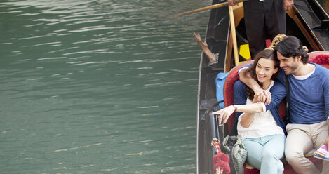 Lächelndes Paar, das in einer Gondel auf einem Kanal in Venedig fährt - CAIF00318