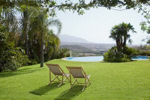 Lawn chair in grass overlooking swimming pool - CAIF00346