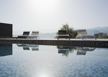 Die Sonne scheint auf die Liegestühle und das Schwimmbecken - CAIF00390