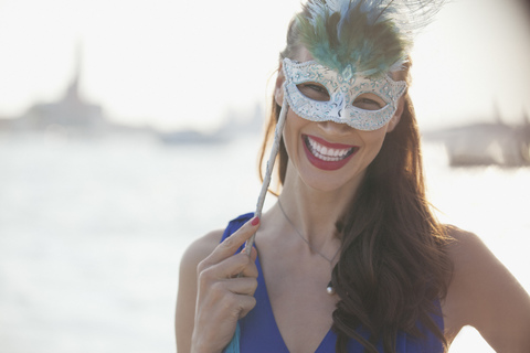 Porträt einer lächelnden Frau mit Maske an der Uferpromenade in Venedig, lizenzfreies Stockfoto