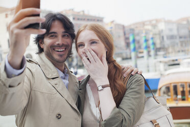 Laughing couple taking self-portrait with camera phone in Venice - CAIF00457