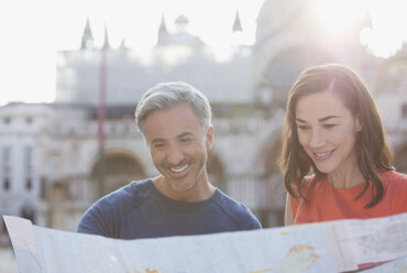 Lächelndes Paar mit Blick auf die Karte in Venedig - CAIF00462