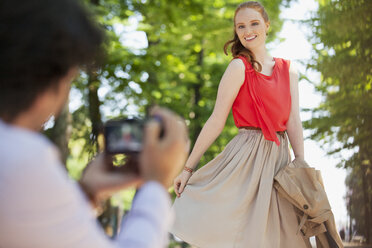 Man photographing woman in park - CAIF00468