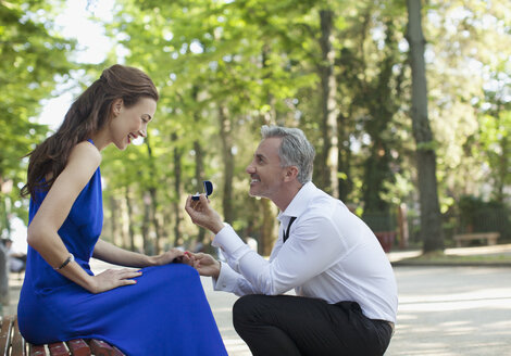 Mann mit Verlobungsring macht seiner Freundin im Park einen Heiratsantrag - CAIF00485