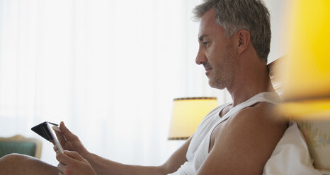 Man using digital tablet in bed - CAIF00488