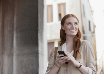 Smiling woman holding cell phone - CAIF00497