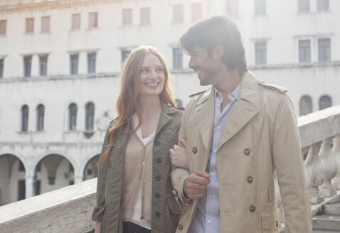 Lächelndes Paar spaziert Arm in Arm in Venedig - CAIF00510