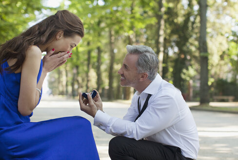 Mann mit Verlobungsring macht einer überraschten Frau einen Heiratsantrag - CAIF00513