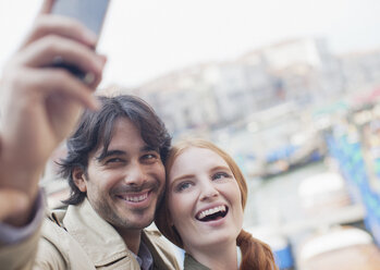 Smiling couple taking self-portrait with cell phone - CAIF00518