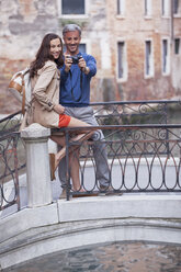 Smiling couple taking self-portrait on footbridge in Venice - CAIF00541