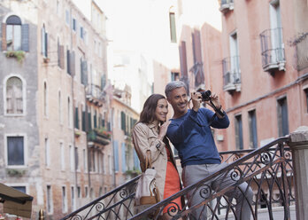 Smiling couple taking photograph in Venice - CAIF00545