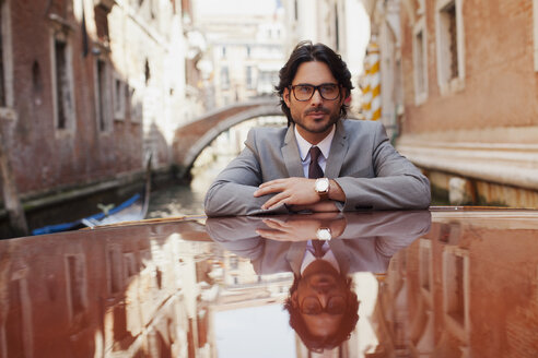 Porträt eines seriösen Geschäftsmannes auf einem Boot im Kanal in Venedig - CAIF00565