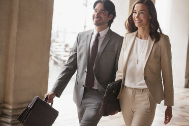 Smiling businessman and businesswoman walking - CAIF00581