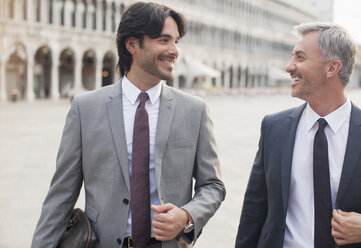 Smiling businessmen talking in St. Mark's Square in Venice - CAIF00592