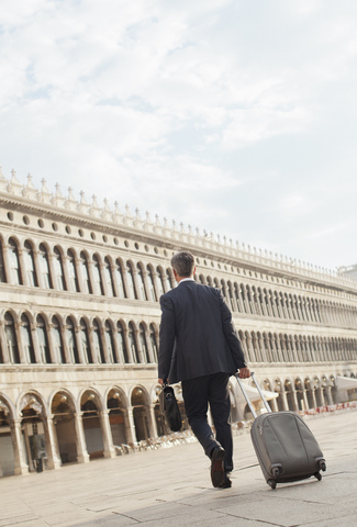 Geschäftsmann, der einen Koffer über den Markusplatz in Venedig zieht, lizenzfreies Stockfoto