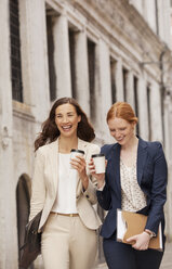 Lächelnde Frauen beim Spaziergang mit Kaffee - CAIF00607