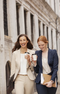 Lächelnde Frauen beim Spaziergang mit Kaffee - CAIF00607