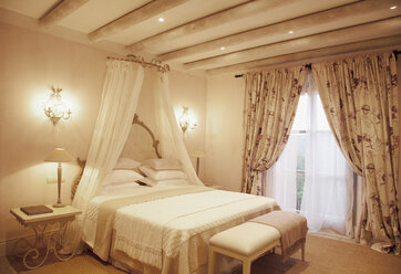 Lichterketten und Baldachin über dem Bett in einem luxuriösen Schlafzimmer - CAIF00628