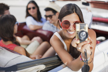 Woman taking picture from convertible - CAIF00669