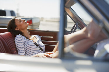 Smiling woman relaxing in convertible - CAIF00683