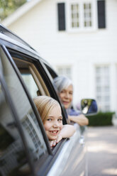 Older woman and granddaughter leaning out car windows - CAIF00708