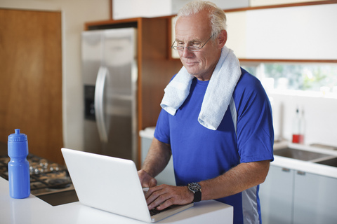 Älterer Mann benutzt Laptop nach dem Training, lizenzfreies Stockfoto