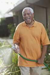 Older men watering plants in backyard - CAIF00740