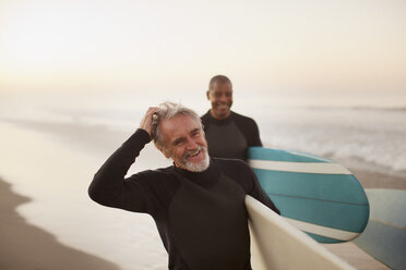 Older surfers carrying boards on beach - CAIF00865