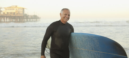 Älterer Surfer mit Brett am Strand - CAIF00873