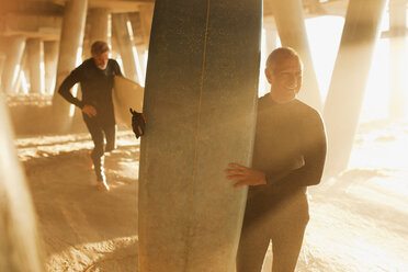 Ältere Surfer tragen Bretter unter dem Pier - CAIF00878
