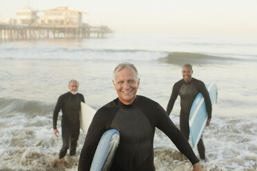 Older surfers carrying boards on beach - CAIF00884