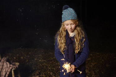 Girl playing with sparkler outdoors - CAIF00902